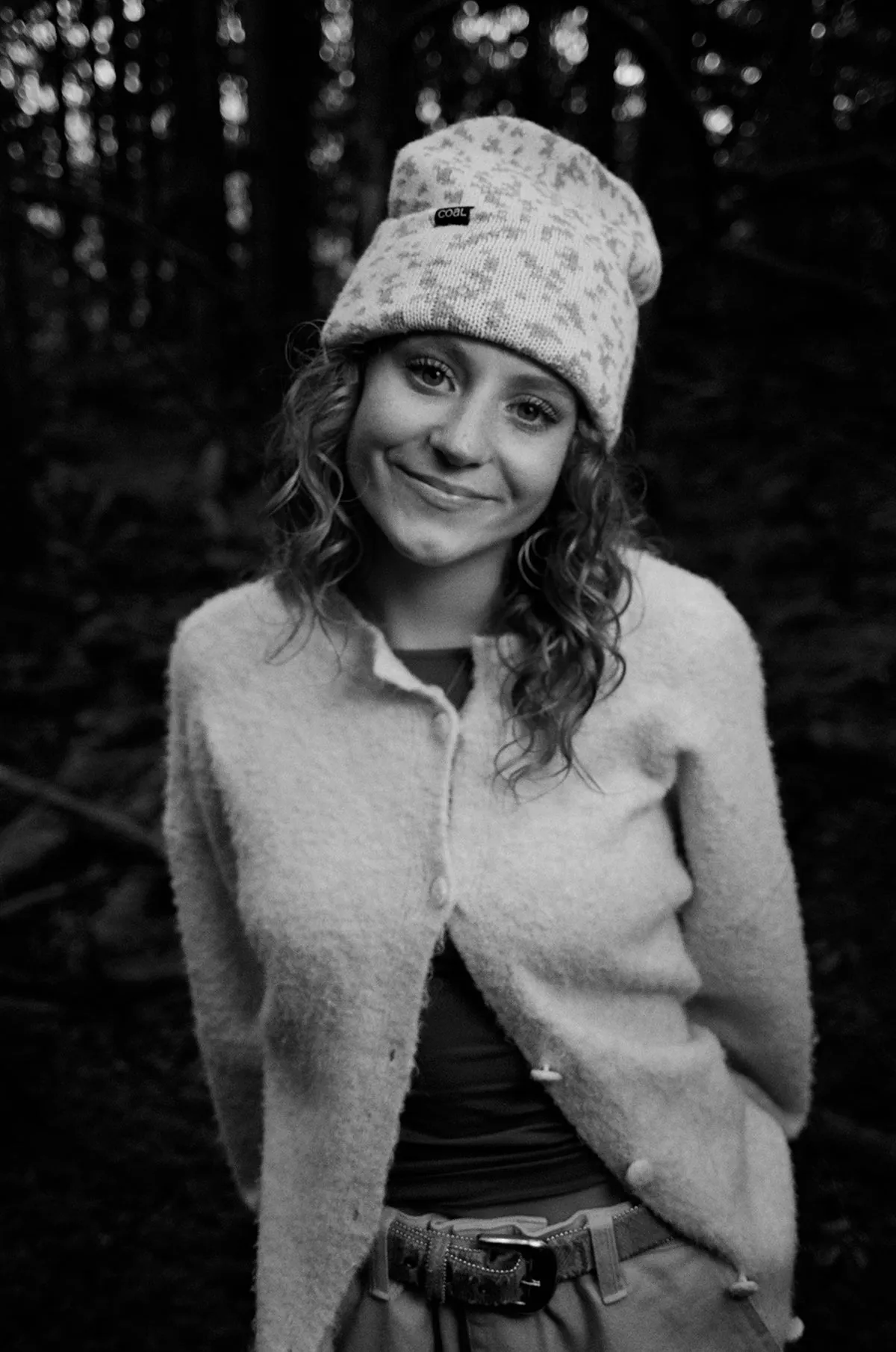 Black and white portrait of Veda Hallen in a knit beanie in the woods