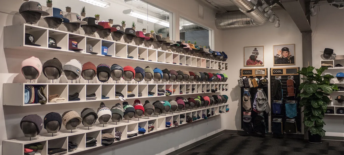 Showroom wall lined with rows of Coal hats on shelves
