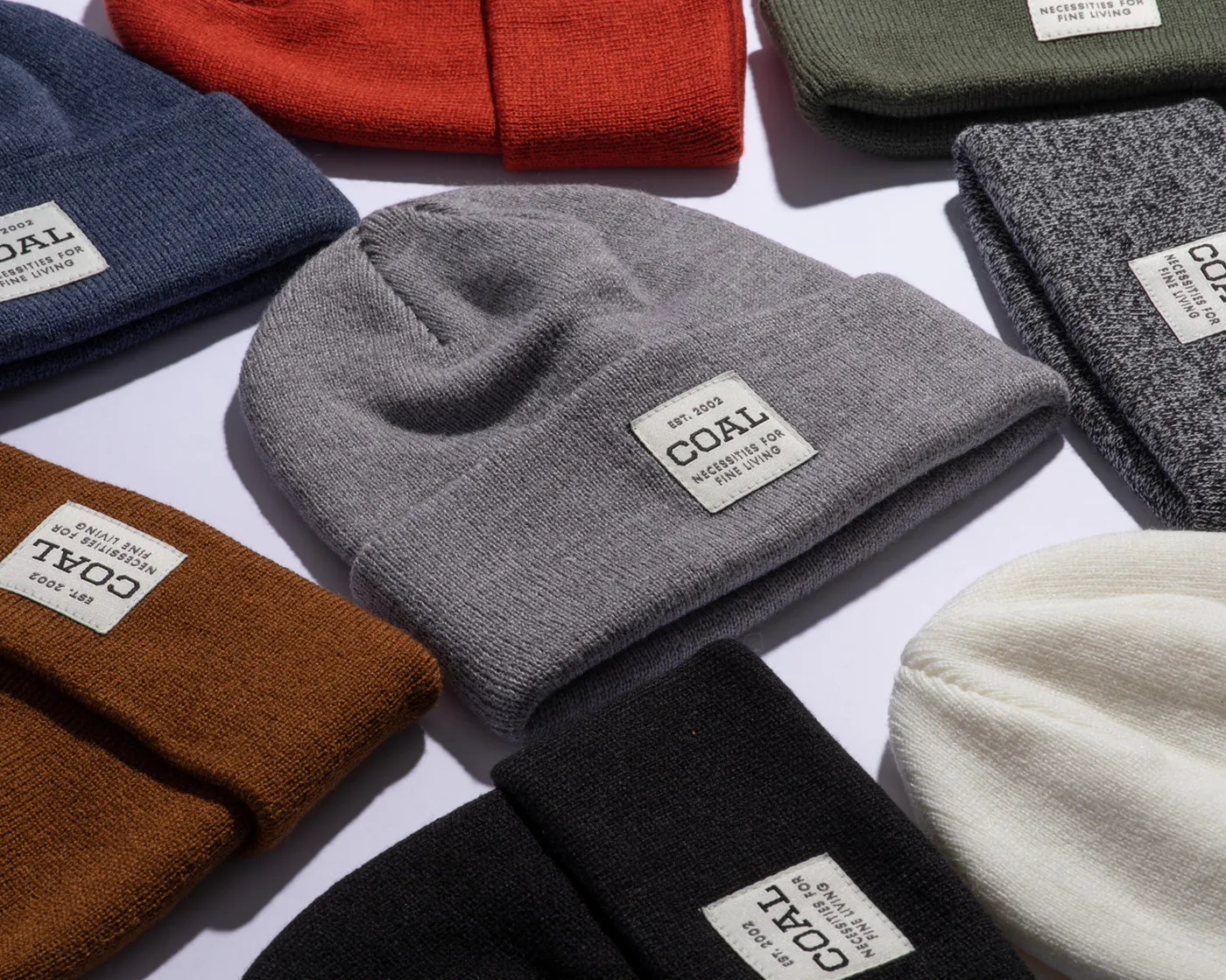 A pile of Uniform beanies in navy, rust, grey and black with the Coal label