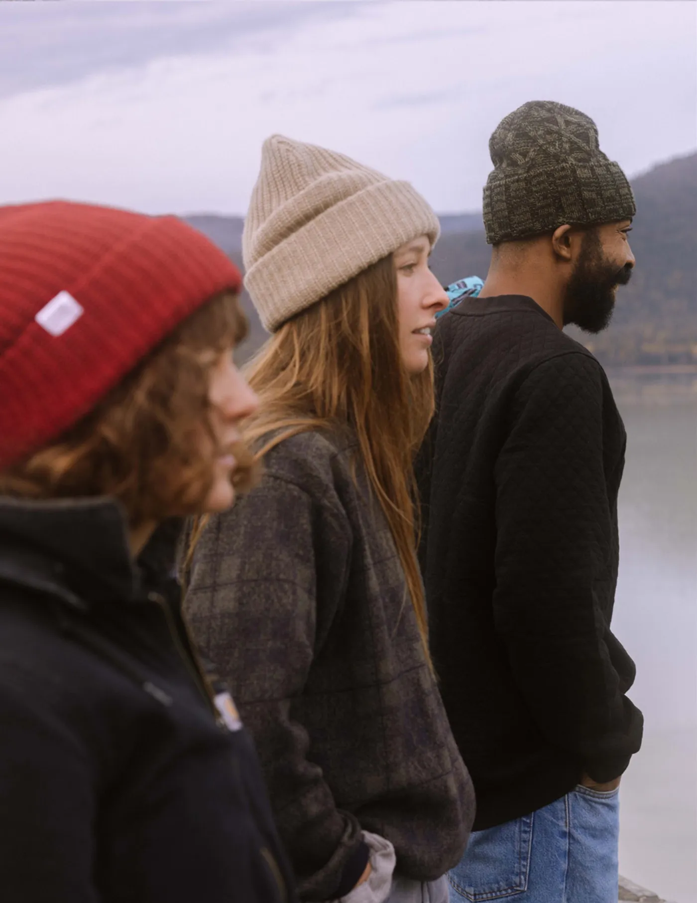 Three friends in Coal beanies talking outside in winter light