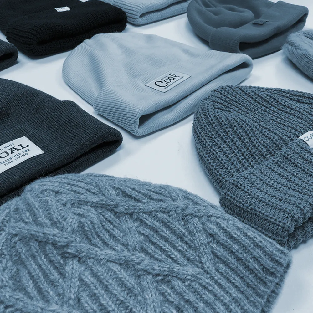 Blue-toned photo of several Coal beanies of different lengths laid side by side